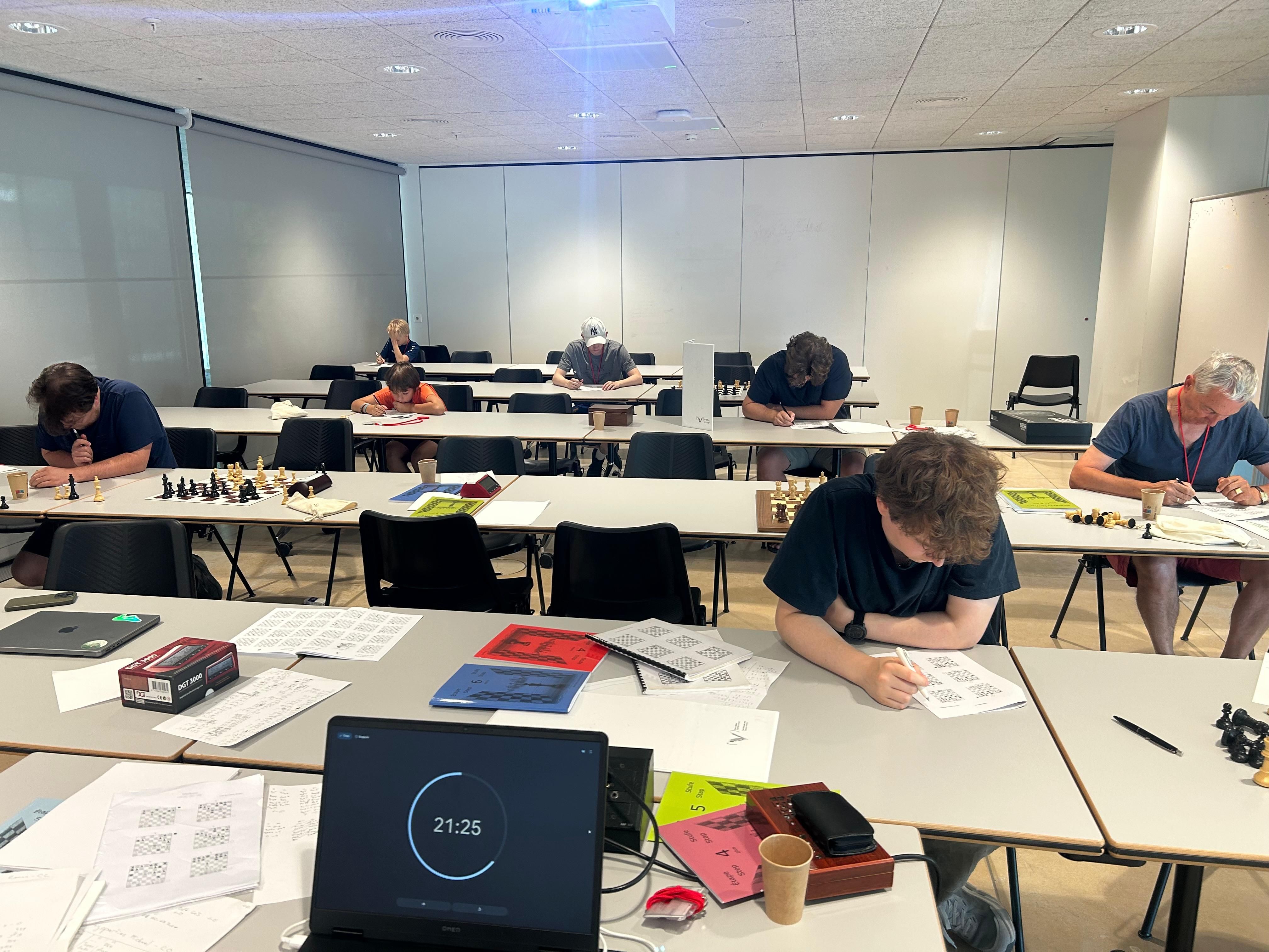 Teilnehmende eines Schachtrainings arbeiten an Schachbrettern und Aufgabenblättern in einem hellen Seminarraum
